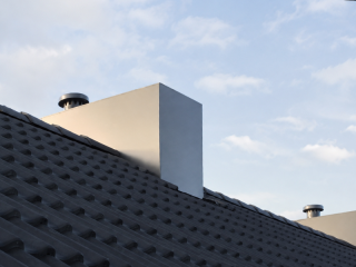 Prefab nokschoorsteen met strakke aluminium mantel en rookgasafvoer op een hellend pannendak.